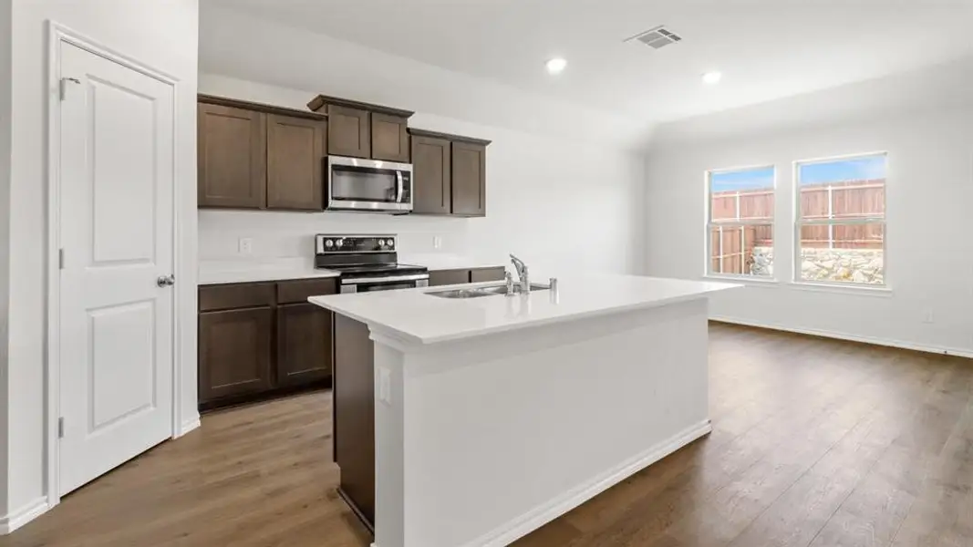 Modern kitchen featuring a central island with an integrated sink and gooseneck faucet