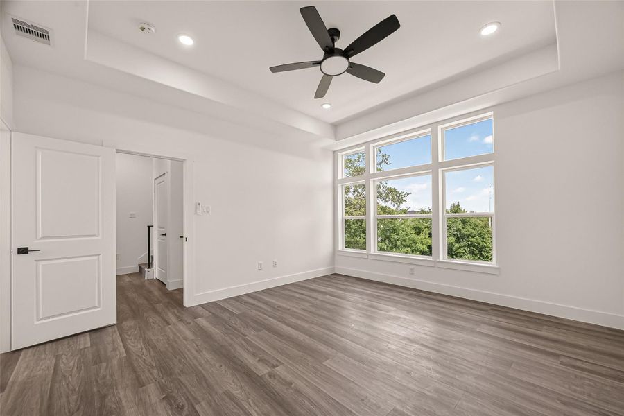 This bright, spacious bedroom features large windows with a scenic view, modern wood flooring, recessed lighting, and a ceiling fan. This bright, spacious bedroom features large windows with a scenic view, modern wood flooring, recessed lighting, and a ceiling fan.