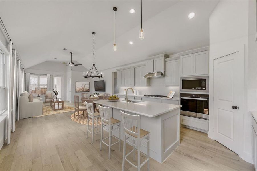 Virtually Staged Photo - Kitchen featuring stainless steel appliances, vaulted ceiling, a breakfast bar, a center island with sink, and light wood-style flooring
