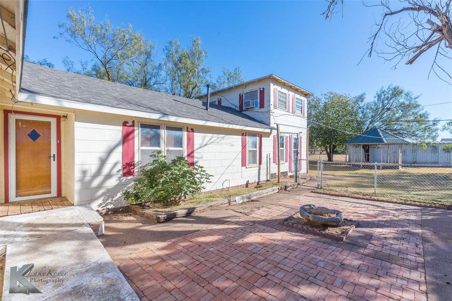 View of front of property featuring a shingled roof, a patio, and a fire pit View of front of property featuring a shingled roof, a patio, and a fire pit