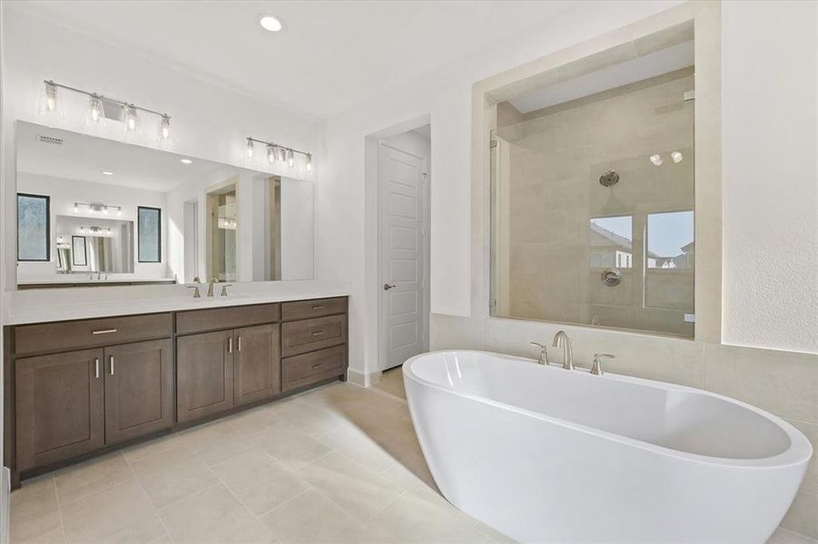 Full bathroom featuring a freestanding bath, vanity, a shower stall, light tile patterned floors, and recessed lighting