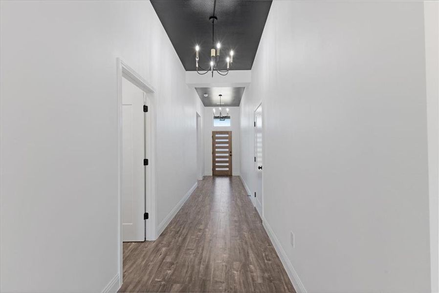 Corridor featuring an inviting chandelier, baseboards, and wood finished floors