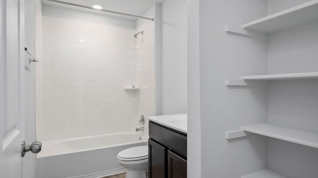 Bathroom featuring vanity,  shower combination, and a textured wall