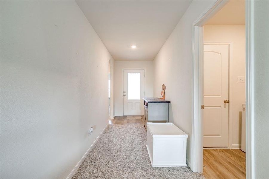 Hallway with baseboards and light colored carpet