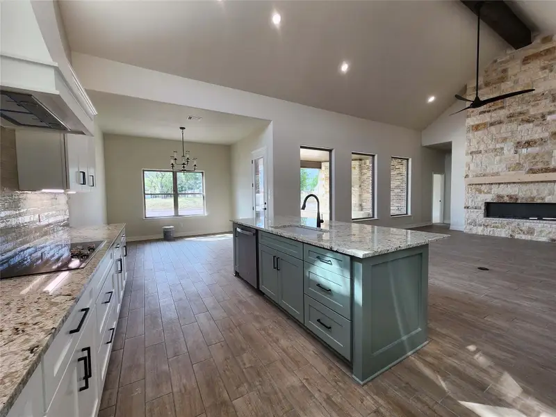 Kitchen with open floor plan, a ceiling fan, light stone counters, dark wood finished floors, and two tone color scheme