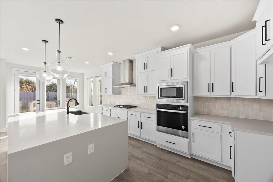 Bright, modern kitchen with sleek white cabinetry, stainless steel appliances, and a large island with pendant lighting. Ample natural light from large windows and access to a patio. Bright, modern kitchen with sleek white cabinetry, stainless steel appliances, and a large island with pendant lighting. Ample natural light from large windows and access to a patio.