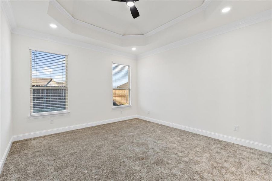 Carpeted empty room with ceiling fan, recessed lighting, baseboards, ornamental molding, and a tray ceiling Carpeted empty room with ceiling fan, recessed lighting, baseboards, ornamental molding, and a tray ceiling