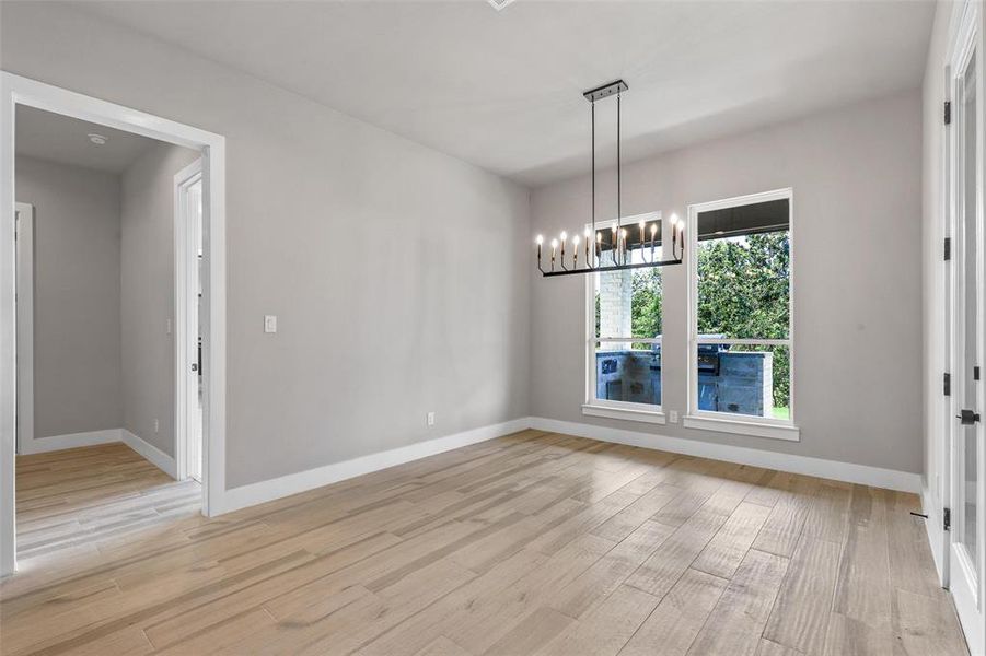 Dining room with light wood-type flooring and an inviting chandelier