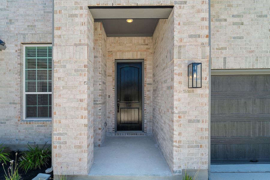A welcoming entry, with a paneled black door and a well-maintained brick exterior.