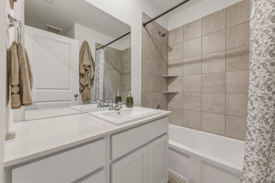 This bathroom features a vanity with a white countertop and a rectangular sink, complemented by a large wall-mounted mirror