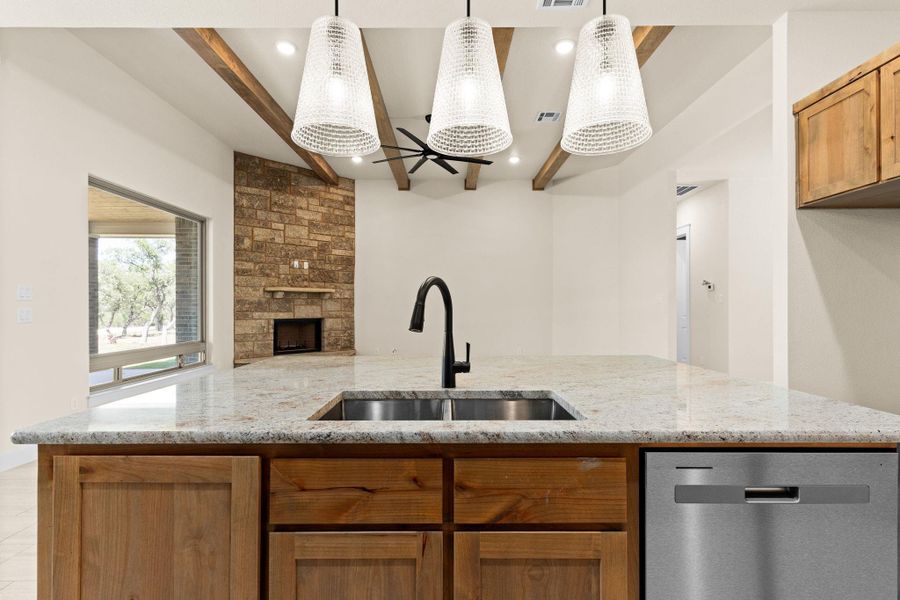 Kitchen with brown cabinets, light stone counters, dishwasher, beam ceiling, and recessed lighting Kitchen with brown cabinets, light stone counters, dishwasher, beam ceiling, and recessed lighting