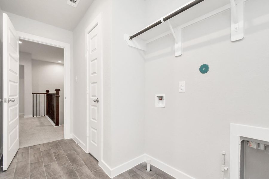 A perfect blend of functionality and comfort. Laundry room, thoughtfully equipped with shelving for effortless organization. Both gas and electric connections available. Sample photo of completed home with similar floor plan. As-built interior colors and selections may vary.