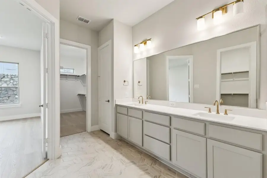 Full Primary bathroom with double vanity, a walk in closet, and marble look tiles