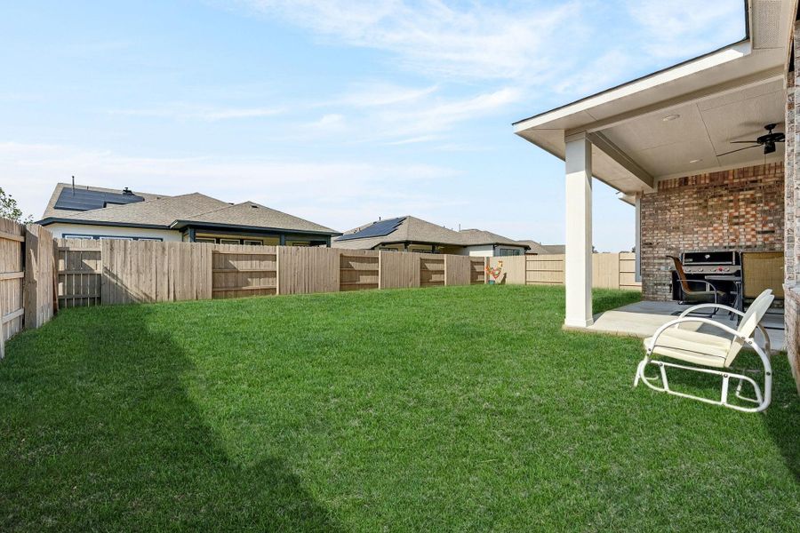 Fenced backyard featuring automatic sprinklers.