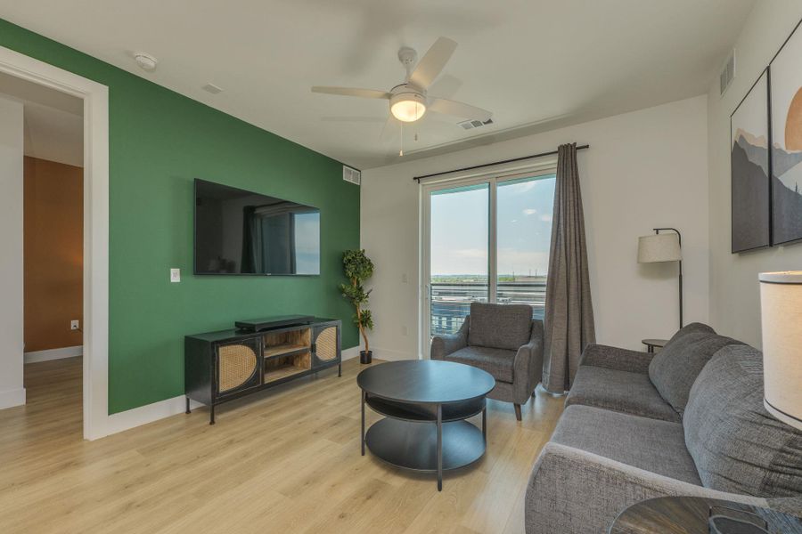 The living area features light wood flooring and a bold accent wall