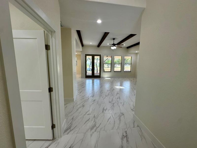 Corridor with light marble finish floors and beam ceiling