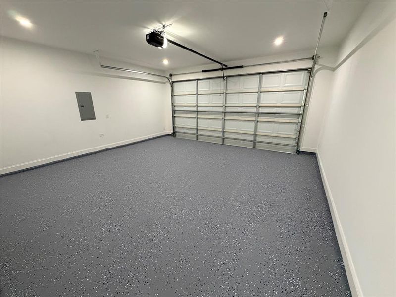 Spacious garage featuring a durable epoxy speckled floor, recessed lighting, white walls, and an automatic garage door opener Spacious garage featuring a durable epoxy speckled floor, recessed lighting, white walls, and an automatic garage door opener