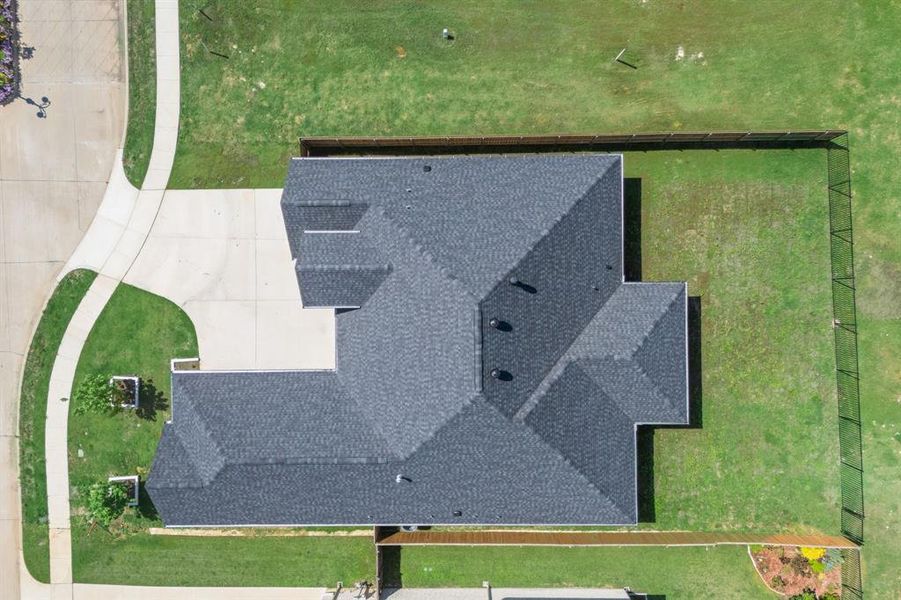 Newly constructed residence featuring a dark shingle roof and a spacious concrete driveway Newly constructed residence featuring a dark shingle roof and a spacious concrete driveway