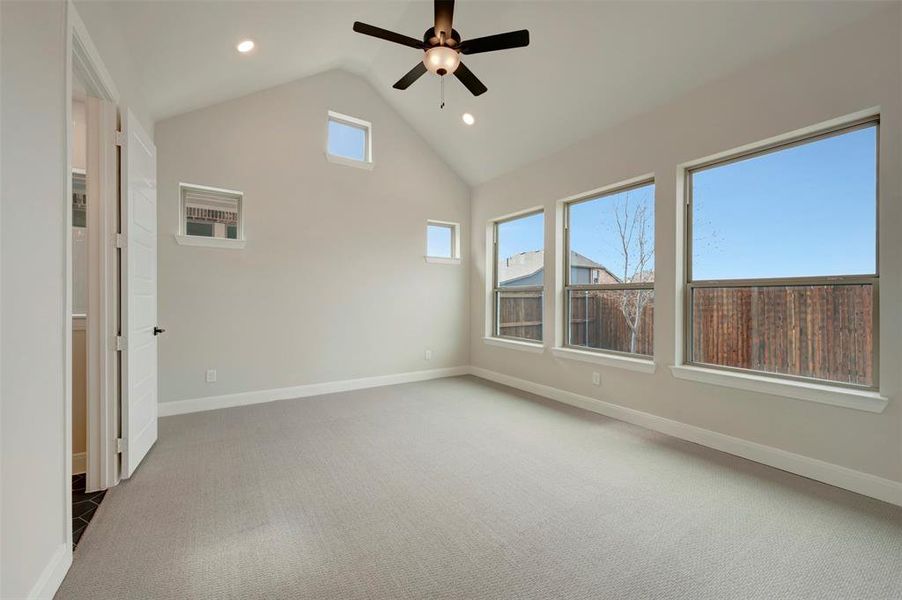 Spare room featuring light colored carpet, a ceiling fan, recessed lighting, and a high ceiling