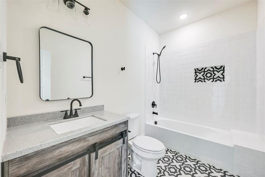 Bathroom featuring a wood-finish vanity with sliding barn-door style hardware, a light-toned countertop, and an undermount sink Bathroom featuring a wood-finish vanity with sliding barn-door style hardware, a light-toned countertop, and an undermount sink