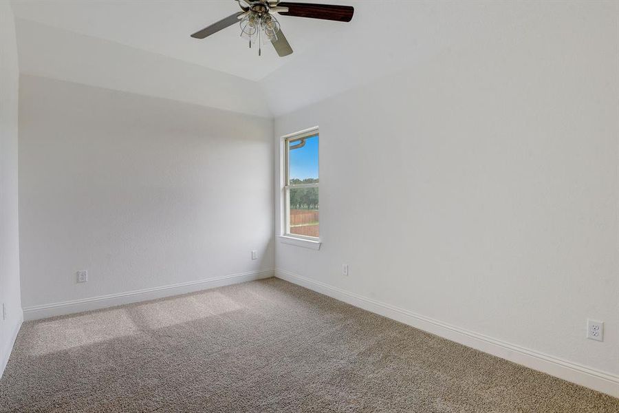 Empty room with ceiling fan, carpet floors, and lofted ceiling