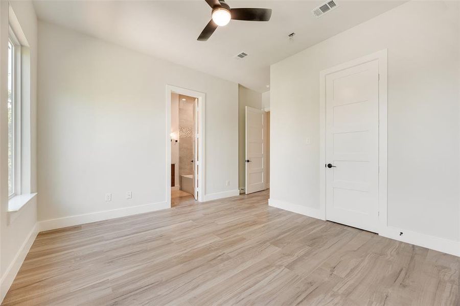 Unfurnished bedroom with light wood-type flooring, ceiling fan, and ensuite bath Unfurnished bedroom with light wood-type flooring, ceiling fan, and ensuite bath