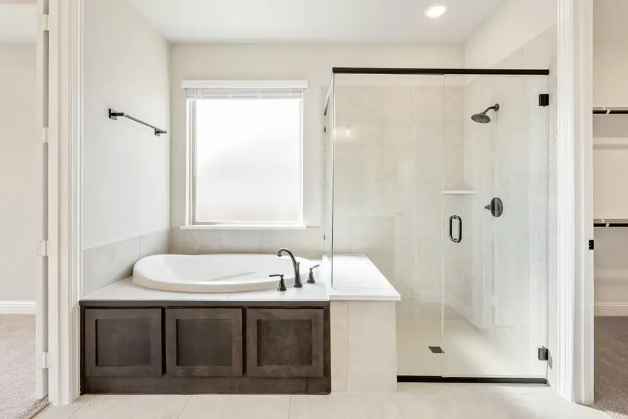 Master bathroom with soaking tub, dark wood surround, and glass-enclosed walk-in shower with tile walls