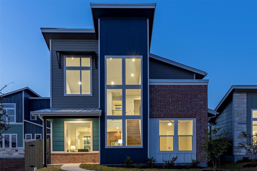 Back of property featuring a metal roof, brick siding, board and batten siding, and a standing seam roof