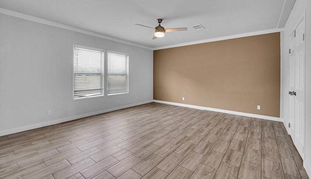 Empty room featuring crown molding, wood tiled floors, and a ceiling fan Empty room featuring crown molding, wood tiled floors, and a ceiling fan