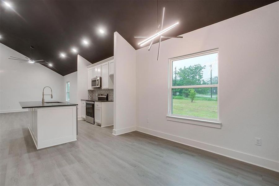 Kitchen featuring stainless steel appliances, dark countertops, tasteful backsplash, white cabinetry, and a ceiling fan