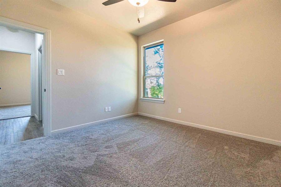 Carpeted empty room featuring baseboards and ceiling fan