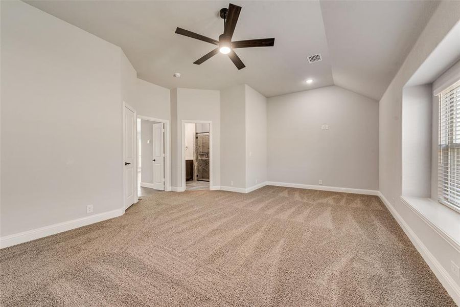 Unfurnished bedroom featuring light carpet, vaulted ceiling, ensuite bath, and ceiling fan Unfurnished bedroom featuring light carpet, vaulted ceiling, ensuite bath, and ceiling fan