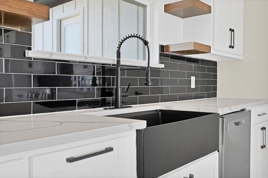 Kitchen featuring white cabinetry, dishwasher, backsplash, and light stone counters