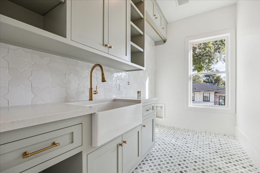 Second floor utility room has designer tile and farm sink. Second floor utility room has designer tile and farm sink.