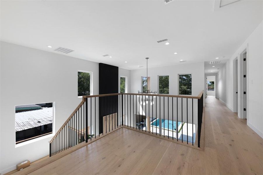 Hall with light wood finished floors, recessed lighting, and an upstairs landing