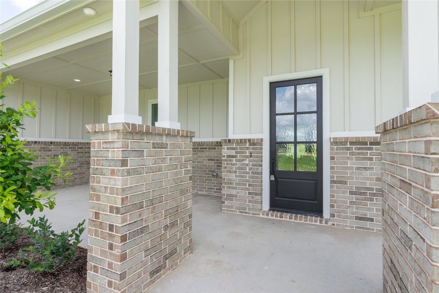 Inviting front porch with a brick and black paneled door. Inviting front porch with a brick and black paneled door.