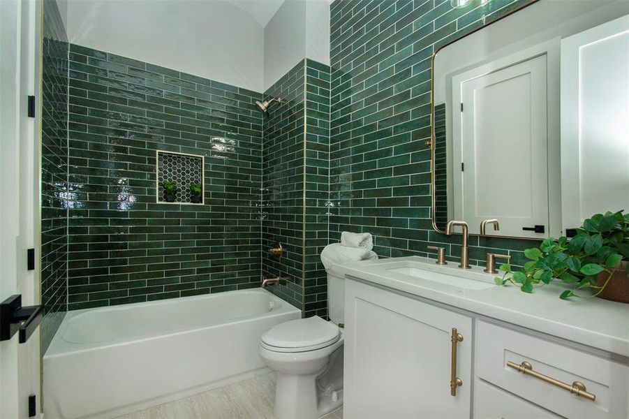 Full bathroom featuring hardwood / wood-style floors, vanity, tiled shower / bath, toilet, and tasteful backsplash