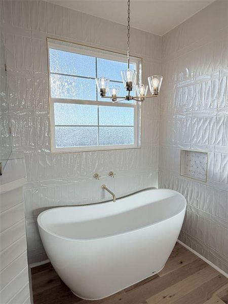 Bathroom featuring hardwood / wood-style flooring, tile walls, a freestanding bath, and hanging lights Bathroom featuring hardwood / wood-style flooring, tile walls, a freestanding bath, and hanging lights