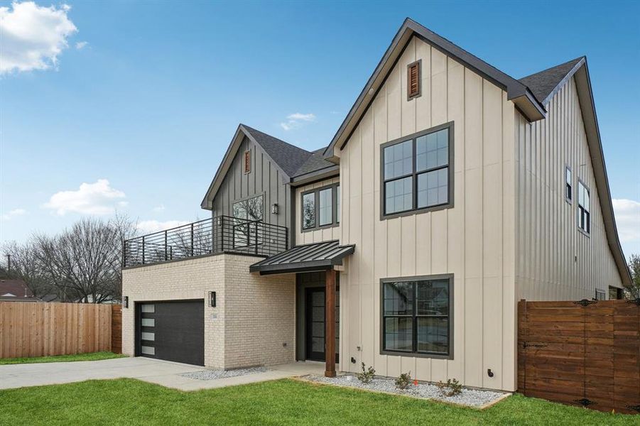 View of front of home featuring board and batten siding, brick siding, a standing seam roof, and driveway