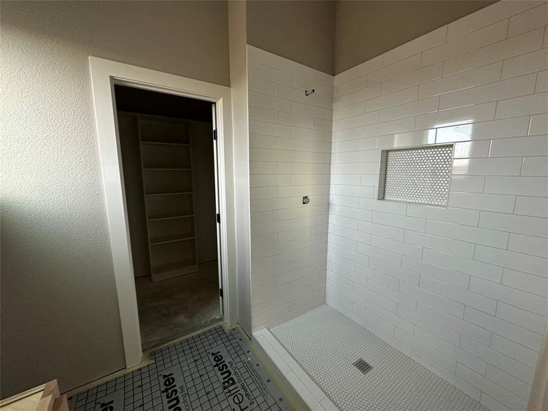 Bathroom with tiled shower and tile patterned floors