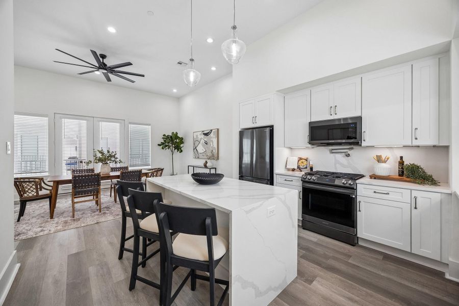 Sleek gourmet kitchen features a quartz waterfall kitchen island with plenty of extra seating and storage. Sleek gourmet kitchen features a quartz waterfall kitchen island with plenty of extra seating and storage.