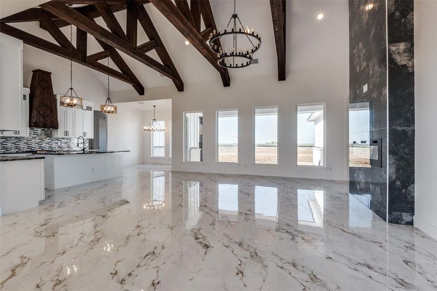 Unfurnished living room featuring beamed ceiling and high vaulted ceiling