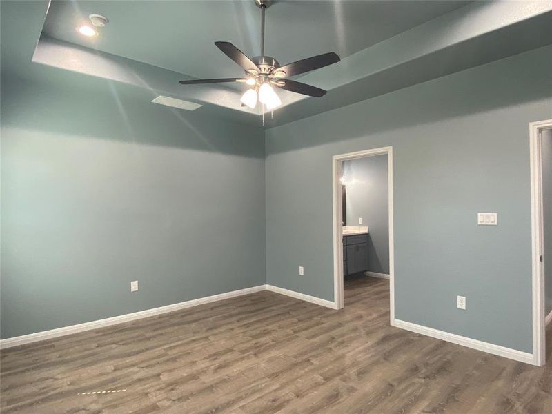 A tranquil primary suite with warm wood flooring opens to an ensuite bathroom. A tranquil primary suite with warm wood flooring opens to an ensuite bathroom.