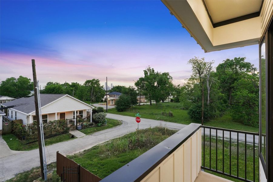 Private second-story balcony overlooking a quiet neighborhood and lush green space, offering peaceful twilight views and an inviting outdoor retreat ideal for relaxing or entertaining.