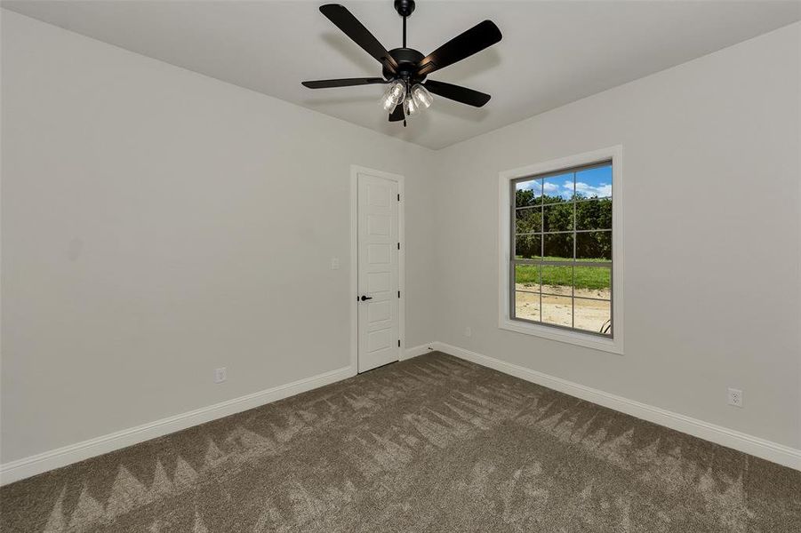Empty room featuring dark carpet and ceiling fan