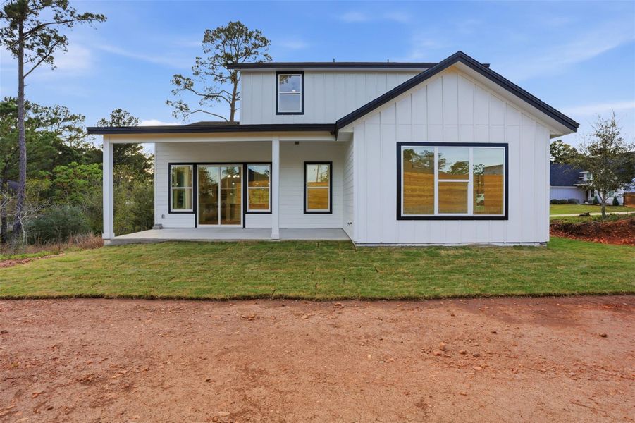 Rear view of house with a patio, board and batten siding, and a yard