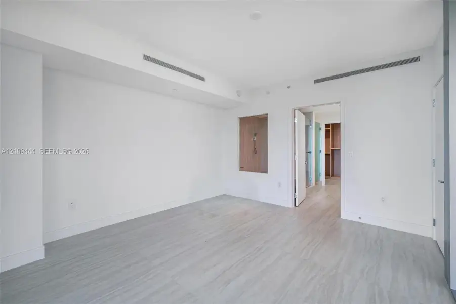 Neutral interior featuring wood-finish flooring, recessed ceiling linear diffusers, and a built-in recessed wall niche