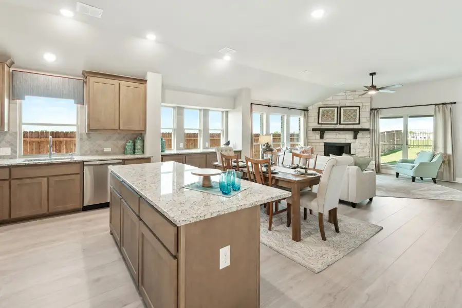 Open-concept kitchen with granite island flowing into dining area and living room with stone fireplace and hardwood floors Open-concept kitchen with granite island flowing into dining area and living room with stone fireplace and hardwood floors