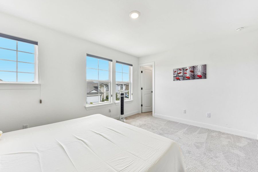 Rest peacefully in this airy bedroom, naturally illuminated by multiple windows.