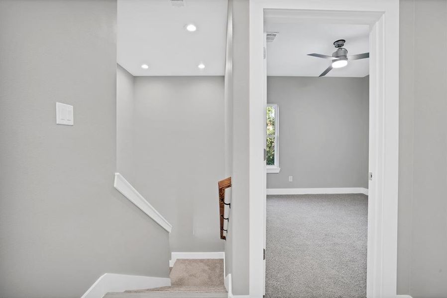 Stairway with carpet flooring and ceiling fan